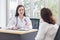 Asian professional doctor woman who wears medical coat talks with woman patient to suggest treatment guideline and healthcare