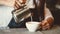 Asian professional female barista pouring milk in latte art coffee at counter bar in cafeteria restaurant as shop owner. Waitress