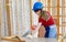 Asian professional female engineer architect foreman labor worker wears safety goggles hard helmet and jeans apron using handsaw