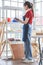 Asian professional female labor worker wears safety goggles and apron standing holding paper clipboard writing note checking stock