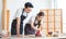 Asian professional male carpenter in apron complimenting showing thumb up to female lover worker using polishing machine rubbing