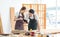 Asian professional male and female carpenter worker lover couple in apron standing smiling helping looking at short notes on paper