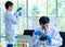 Asian professional mature male scientist in white lab coat and rubber gloves using microscope magnifying science sample on