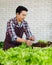 Asian professional successful cheerful male farmer gardener in apron standing smiling harvesting holding fresh raw organic green