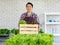 Asian professional successful cheerful male farmer gardener in apron standing smiling harvesting holding fresh raw organic green