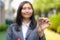 Asian real estate agent or realtor woman smiling and holding red file with showing house key in front of thier house in summer day