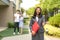 Asian real estate agent or realtor woman smiling and holding red file with thumb up with happy Asian couple hugging in front of