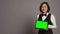 Asian receptionist holding tablet with greenscreen on camera,