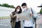 Asian romantic couple wear mask, travel in the city for honeymoon trip. New marriage man and woman backpacker tourist look at map