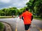 Asian runner wear orange shirt Jogging in the city central park