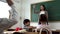 Asian school teacher with students raising hands. Young woman working in school with arm raised, school children putting