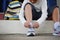 Asian schoolboy in casual clothing tying shoelaces on sneakers getting ready for school or traveling