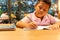 Asian schoolboy hand with pencil doing his homework at home.