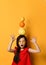 Asian schoolgirl in sunglasses, red blouse, colored skirt. Amazed, holding pomelo, orange and lemon on her head, posing in studio