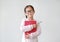 Asian schoolgirl wearing eyeglass hug a book and holding pencil in hand against white background. Portraits of child girl looking