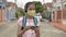 Asian secondary schoolgirl in protective face mask wearing headphones and walking in housing community.
