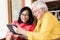 Asian senior couple in love smiling while holding tablet
