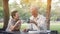 Asian senior couple start morning coffee in park, optimistic and