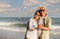 Asian senior couple tourist is hand in hands, embrace and dancing on tropical sea beach in summer holiday