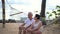 Asian senior elder couple relax talking on hammock at seaside retirement trip