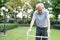 Asian Senior elderly disabled man patient walking slowly with walker or cane at green park. Older mature handicapped male feeling