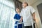 Asian Senior elderly disabled man patient walking slowly with walker at nursing home care. Caregiver therapist nurse support older