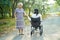 Asian senior or elderly old lady walk with walker in park and woman in wheelchair in park