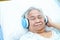 Asian senior or elderly old lady woman patient listen to music while lie down on bed in nursing hospital ward