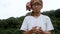 Asian senior holding a magic crystal glass ball in his hands with pray on nature background.