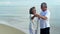 Asian senior love couple dancing on the beach. Retirement age family relaxing and recreation on summer