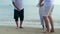 Asian senior love couple with son dancing on the beach. Retirement age family relaxing and recreation on summer