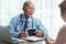 Asian Senior Male doctor in blue shirt talking with his patient