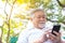 Asian senior man chatting with family by using smart phone, video call, internet wireless at park. His family stay at overseas. Ma