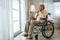 Asian senior man disabled sitting alone in wheelchair looking through window at hospital