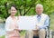 Asian senior man sitting on a wheelchair with caregiver and white board