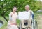 Asian senior man sitting on a wheelchair with caregiver and white board