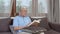 Asian senior men relax at home. Asian Senior Chinese male enjoy rest time read book while lying on sofa in living room at home