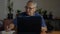 Asian Senior retire man wears eyeglasses working with computer laptop on the desk and writing on a notebook at home.