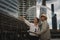 Asian senior traveler couple with map and umbrella having city tour during rainy season