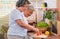 Asian senior wife slicing tomatoes on wooden cutting  board and using tablet computer to searching menu recipe.senior with technol