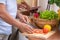 Asian senior wife slicing tomatoes on wooden cutting  board and using tablet computer to searching menu recipe.senior with technol