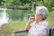 Asian senior woman feeling stressed,worried female bites finger nails in wheelchair outdoor park,elderly people with nervous