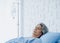 Asian senior woman patient grey hair sleeping on bed in modern white hospital room.