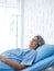 Asian senior woman patient grey hair sleeping on bed in modern white hospital room, vertical style.