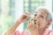 Asian senior woman putting eye drop,closeup view of elderly person using bottle of eyedrops in her eyes,sick old woman suffering