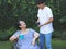 Asian senior woman sitting on wheelchair, drinking coffee or tea with her son in the garden. smiling happily