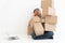 Asian Shopaholic man Shocked and sitting on the floor in the living room and Cardboard Box on top of him after The courier