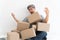 Asian Shopaholic man Shocked and sitting on the floor in the living room and Cardboard Box on top of him after The courier