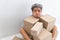 Asian Shopaholic man Shocked and sitting on the floor in the living room and Cardboard Box on top of him after The courier