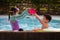 Asian sibling girl and boy playing water with toy together in the swimming pool with fun.